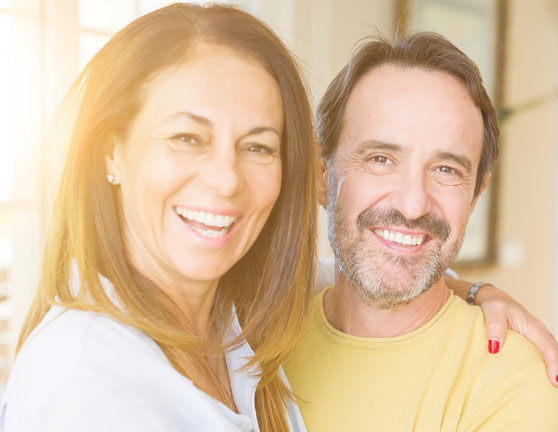 Pareja sonriendo mientras la mujer abraza al hombre