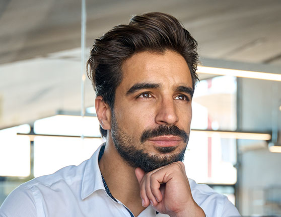 Hombre sentado con la mano en la barbilla, mirando al horizonte