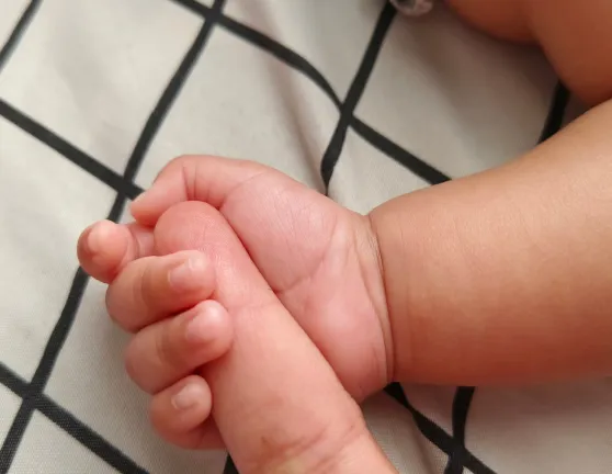Mano de bebé agarrando el dedo de una persona adulta